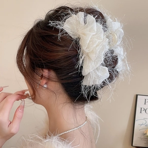 Détail d'une pince à cheveux élégante avec fleurs en tissu blanc et franges