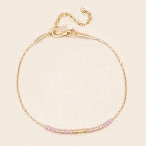 Verstelbare Miyuki-kralenarmband met roze kralen en gouden ketting op beige achtergrond
