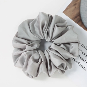 Detailed view of large silver-grey satin hair scrunchie with soft pleated texture