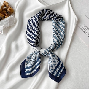 Detail of blue and white silk scarf with letter A pattern tied on a white camisole