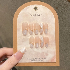 Pink and pearl white press-on nails with gold accents and pearls on a display card