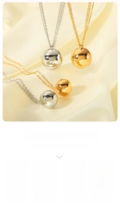 Polished gold and silver ball pendant necklaces on elegant beige silk fabric texture