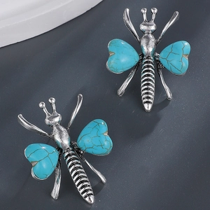 Macro view of vintage bee earrings with turquoise hearts and aged silver finish