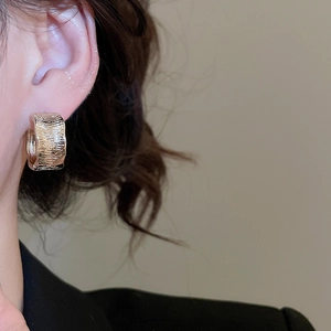 Macro shot of 18K gold plated hoop earrings with luxury irregular crinkled texture