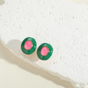 Detailed macro view of oval vintage earrings with green enamel and pink resin stones