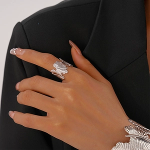 Detailed close-up of silver feather-textured open ring and matching metal cuff bracelet
