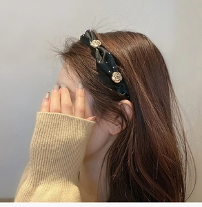 Close-up of black fabric knotted headband with golden rose metal accents worn by model