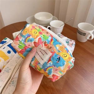 Detailed macro view of quilted cotton cosmetic bag featuring sun and rainbow patterns