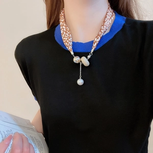 Détail du collier foulard léopard avec perles métalliques et pendentif perle