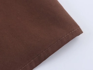 Gros plan détaillé de la texture du tissu marron foncé et des coutures de bord nettes