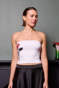 Detail shot of a white strapless crop top featuring a realistic red rose print