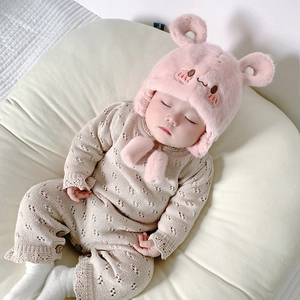 Dettaglio del cappello rosa peluche con orecchie e pagliaccetto in maglia beige