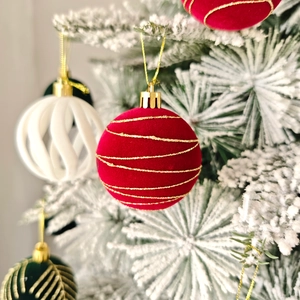 Gros plan d'une boule de Noël floquée rouge avec paillettes dorées sur branche de sapin