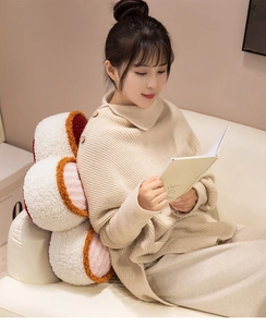 Soft and cozy flower-shaped plush pillow used as a decorative backrest on a white sofa