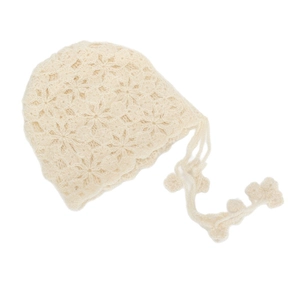 Detail van handgehaakte holle bloemmotieven op een vintage babybonnet met strikbandjes