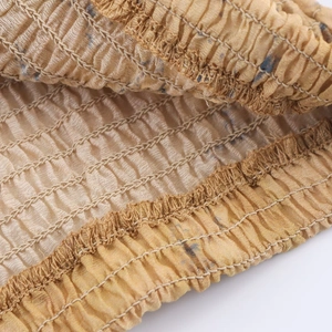 Close-up of golden brown smocked fabric with elastic stitching details on a V-neck top