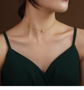 Close-up of gold collar necklace featuring minimalist black rose hollow flower pendants