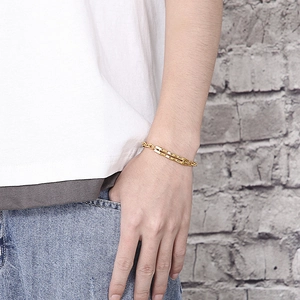 Gros plan d'un bracelet barre en acier inoxydable doré porté sur le poignet
