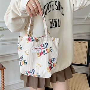 Beige corduroy tote bag with Keep Smiling print and logo tag shown in a casual lifestyle setting