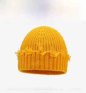 Détail du bonnet en tricot jaune avec bords effilochés et texture de maille épaisse