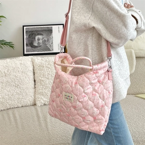 Sac bandoulière rose matelassé avec motif lapin blanc et fleurs porté par un mannequin