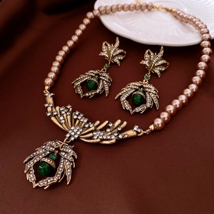 Detail of vintage necklace set with pink pearls, leaf pendants, and green gemstones