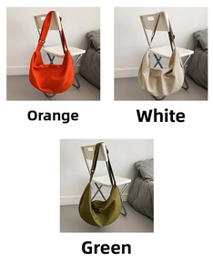 Three large oxford cloth crossbody bags in orange, off-white, and green on a chair