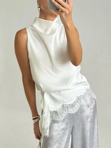 Detail of elegant white satin sleeveless top with floral lace hem and draped high neck collar