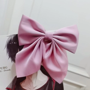 Close-up of a large pink satin bow hair clip with elegant silk texture for styling