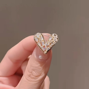 Macro shot of heart-shaped gold-plated brooch with sparkling baguette and round crystals