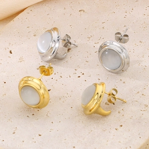 Close-up of elegant gold and silver earrings featuring iridescent round opals on stone