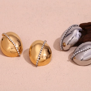 Close-up of bean-shaped gold and silver earrings with inlaid zircon chain detail
