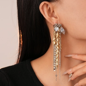 Detail of luxury fringe earrings with gold leaves and silver chains worn by model