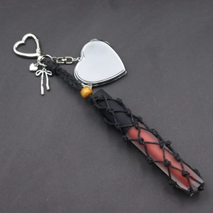 Detail of silver heart-shaped mirror charm with hand-woven lipstick holder net and bead