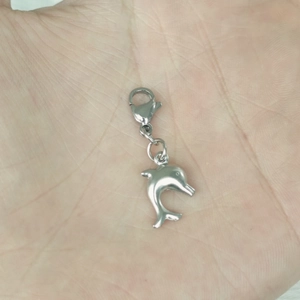 Polished silver stainless steel dolphin pendant with lobster clasp shown on a hand