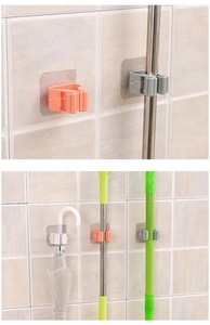 Detail showing self-adhesive wall mounted mop and broom holders on white tile