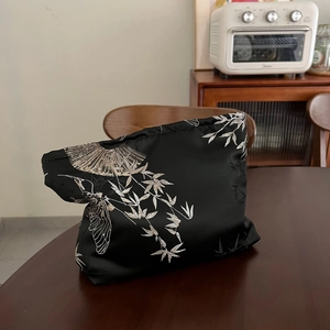 Detailed embroidery of silver bamboo and fan motifs on black satin jacquard makeup bag