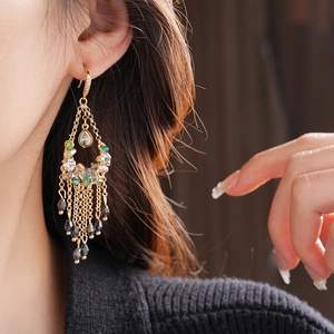 Close-up of tassel earrings featuring zircon droplets and gold chain on a model's ear