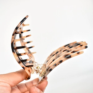 Detail of tortoise shell acetate hair claw clip showing golden metal spring and structure