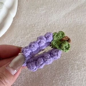 Dettaglio del fermaglio per capelli a uva fatto a mano all'uncinetto con trama in filato viola