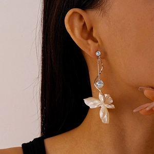 Detail of silver long tassel earrings with sparkling zircon and white petal pendant