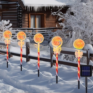 Solar Christmas lollipop garden lights with candy cane stakes and yellow bows in snow