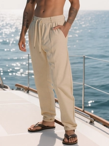 Dettaglio dei pantaloni beige da uomo che mostra la trama in cotone e lino su uno yacht