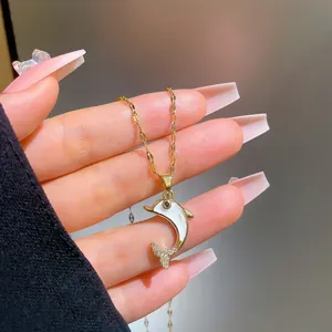 Detail of a gold titanium necklace featuring a micro-set dolphin pendant with shell inlay