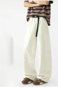 Detalle de pantalones casuales de color blanco roto con pierna ancha y cinturón trenzado negro