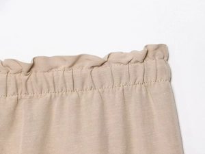 Detailed macro view of the ruffled elastic waistband and drawstring on linen shorts