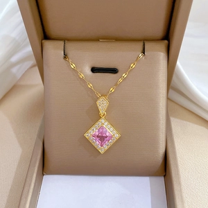 Détail d'un collier en or avec pendentif carré en pierre rose dans un écrin à bijoux