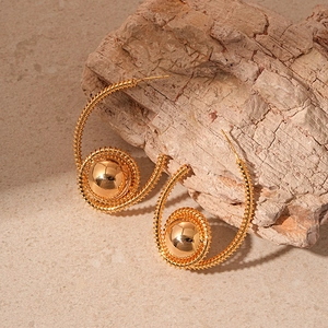 Elegant gold plated spiral hoop earrings with a metallic sphere on natural wood background