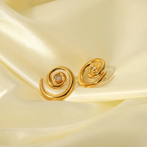 Detailed view of gold spiral earrings with zircon centers on luxury silk background