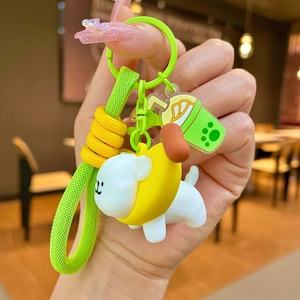Cartoon white puppy keychain in banana outfit with green braided strap and drink charm